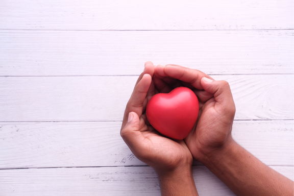 two hands holding a heart-shaped ball.